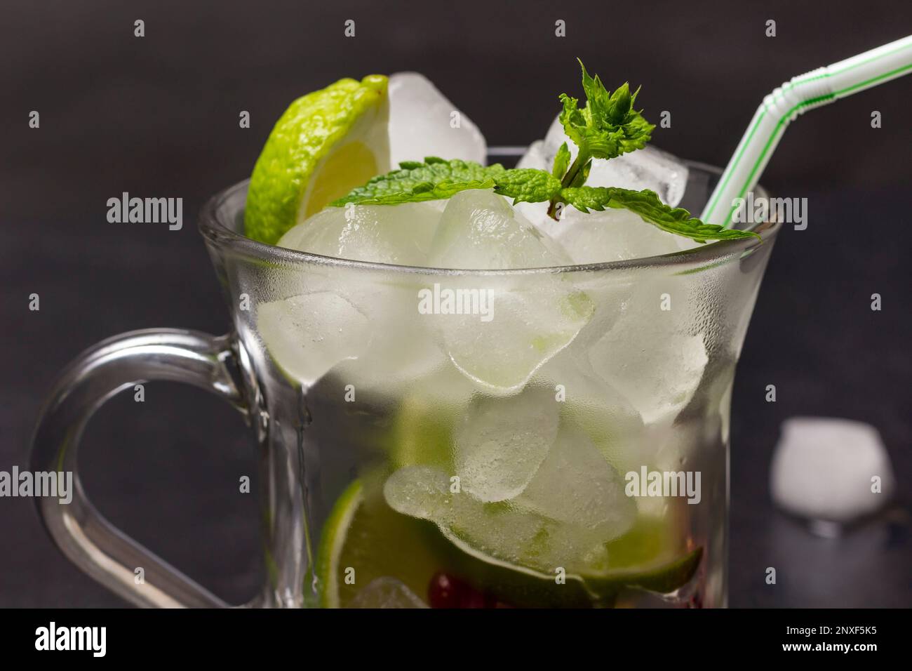 Eis, Zitrone und einen Minzzweig in einem Glas. Teil des Rahmens. Schließen. Grauer Hintergrund. Stockfoto