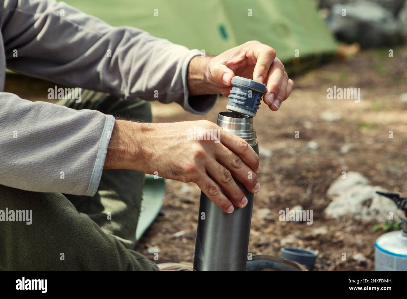 Der Mann stellt Thermosflaschen auf einen Baumstumpf Stockfoto