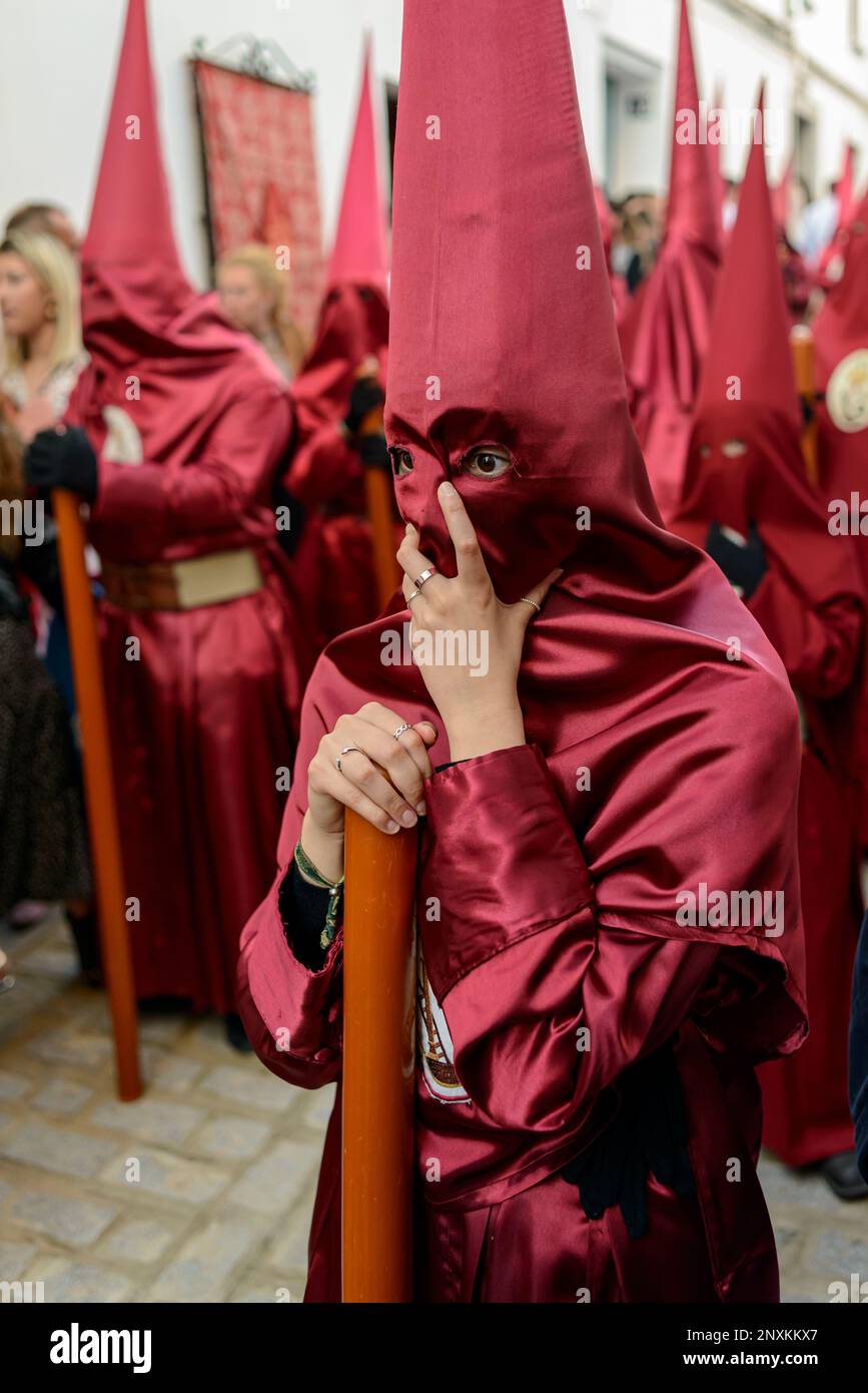 Arahal. Sevilla. Spanien. 14. April 2022. Sie trägt eine rote Tunika und trägt eine Kerze während der Prozessionsprozession am Maundy-Donnerstag. Stockfoto