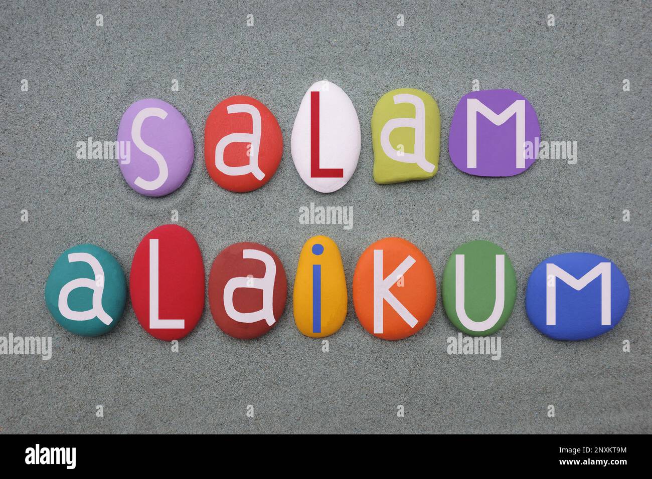 Salam Alaikum-Standardsalutation unter Mitgliedern der Nation of Islam, bestehend aus handgemalten, mehrfarbigen Steinbuchstaben über grünem Sand Stockfoto