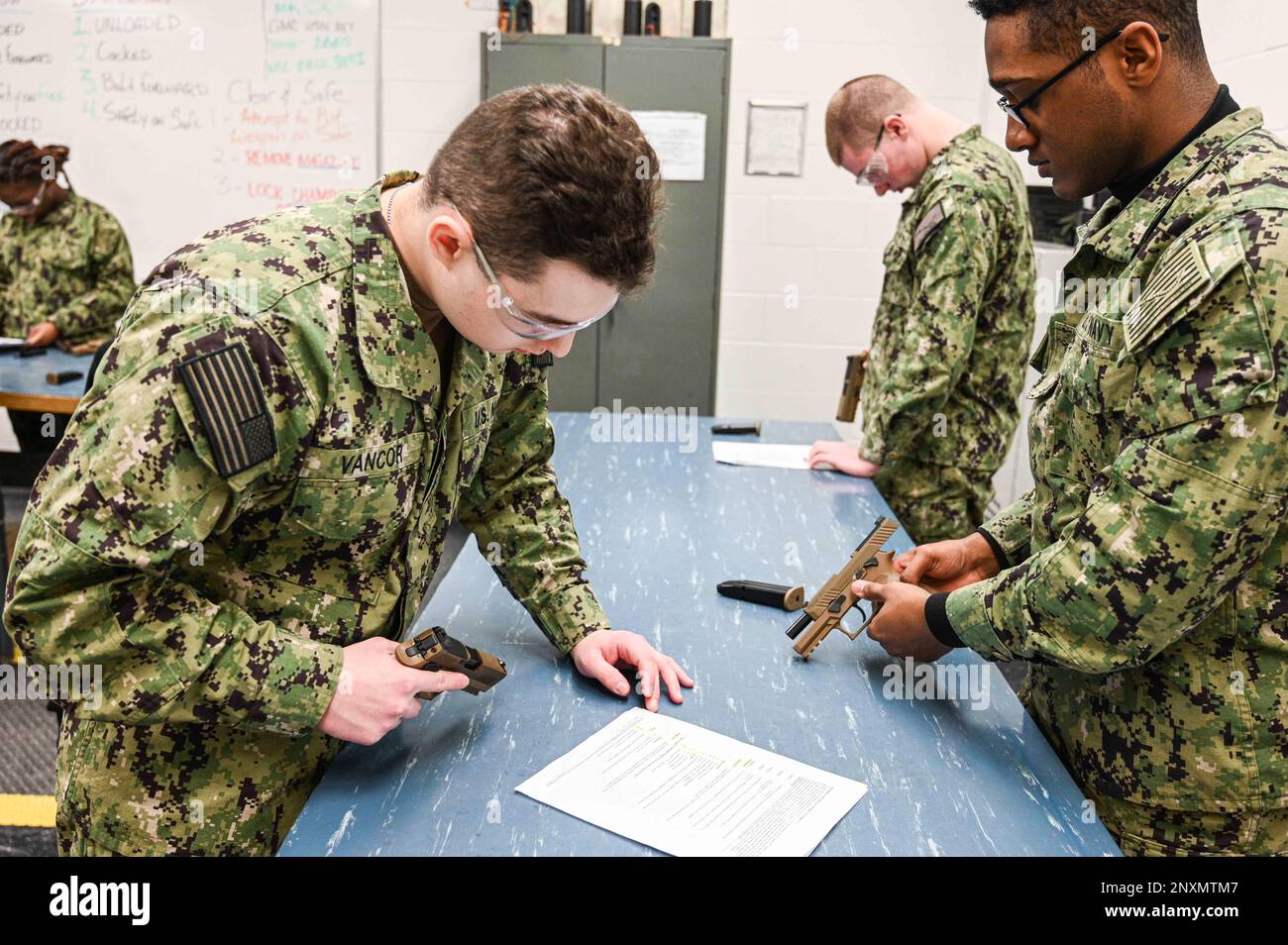 GREAT LAKES, Illinois (3. Februar 2023), Seemannsrekruit Jesse J. Vancor, Right, und SR Justin M. Bellas, beide Schüler des Surface Combat Systems Training Command Great Lakes, bauen M18 Pistolen mit einer Wartungskarte an der Gunner's Mate (GM) „A“ School zusammen. Die GM A-Schule vermittelt Seeleuten technische Ausbildung in Waffenwartung, Elektrizität, Elektronik und Betrieb von Abschusssystemen und Torpedos. Die M9 ist eine Hammerpistole mit Stahlrahmen und einfach-/doppeltwirkender Wirkung. Dies bedeutet, dass es sich um eine schwerere Metallpistole mit zwei verschiedenen Auslösern für einfache und doppelte Wirkung handelt. Umgekehrt ist das M Stockfoto