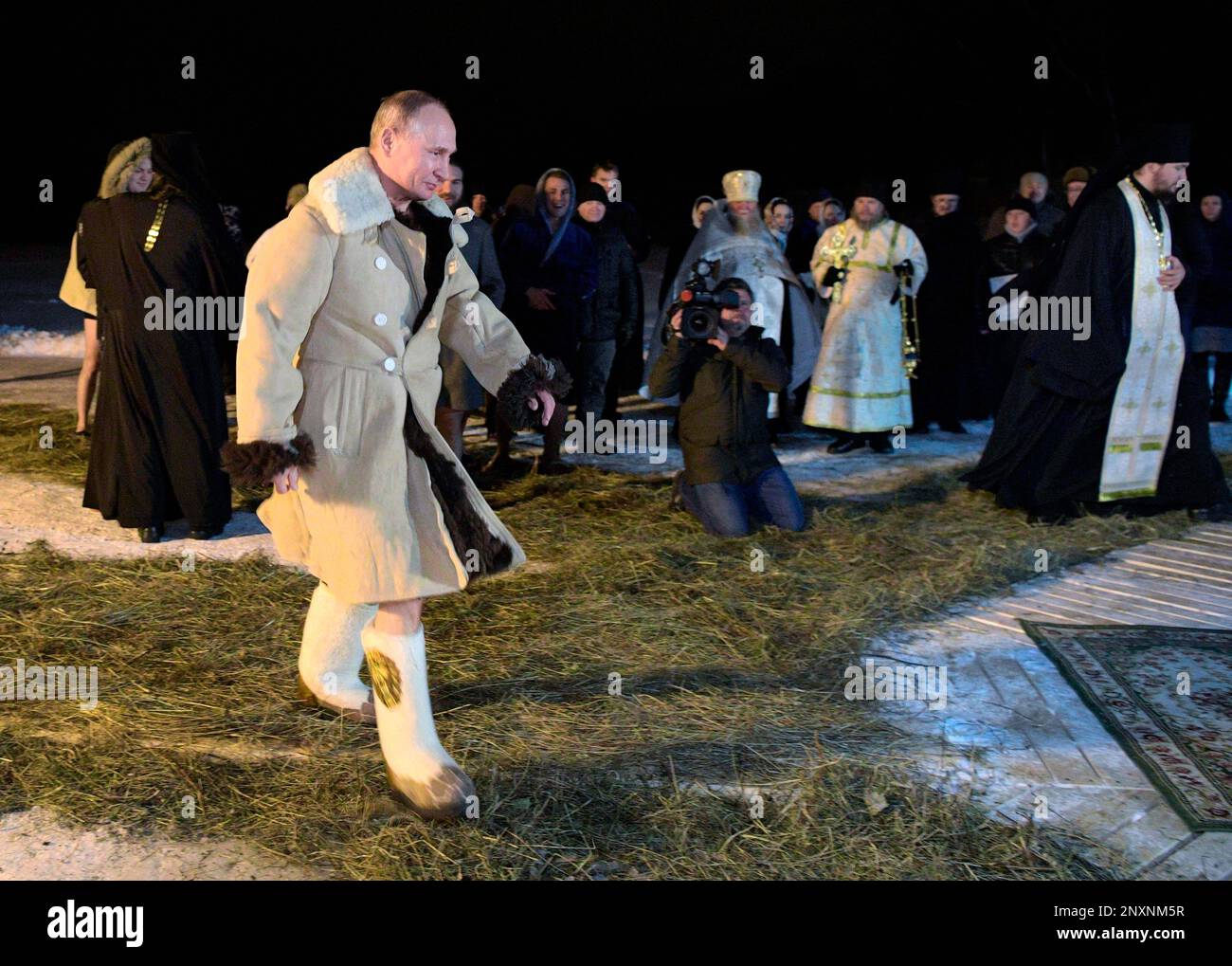 Russian President Vladimir Putin dressed in sheepskin coats walks to bath in an ice-cold water on Epiphany neat St. Nilus Stolobensky Monastery on Lake Seliger in Svetlitsa village, Russia, Friday, Jan. 19, 2018. Thousands of Russian Orthodox Church followers will plunge into icy rivers and ponds across the country to mark Epiphany, cleansing themselves with water deemed holy for the day. (Alexei Druzhinin, Sputnik, Kremlin Pool Photo via AP) Stockfoto