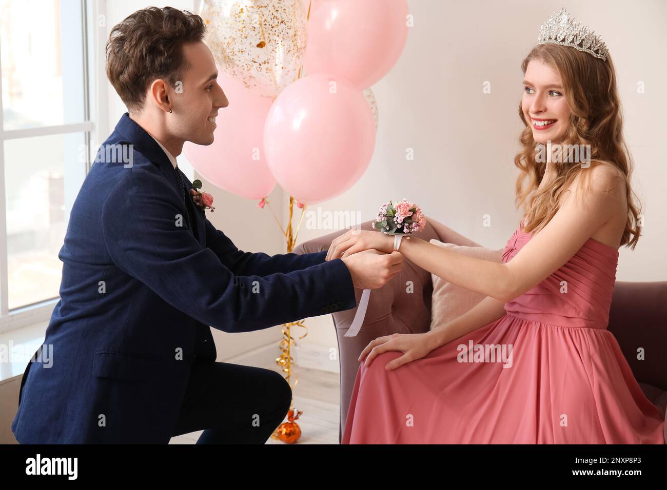 Ein Teenager, der sich beim Abschlussball Ansteckblume um das Handgelenk seiner Freundin bindet Stockfoto
