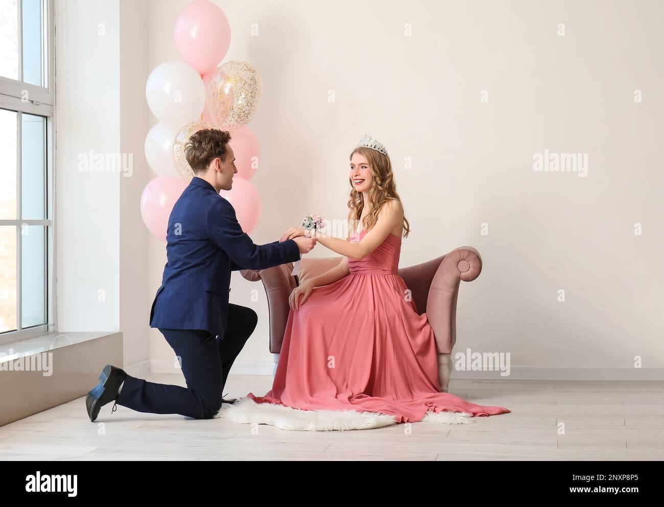 Ein Teenager, der sich beim Abschlussball Ansteckblume um das Handgelenk seiner Freundin bindet Stockfoto