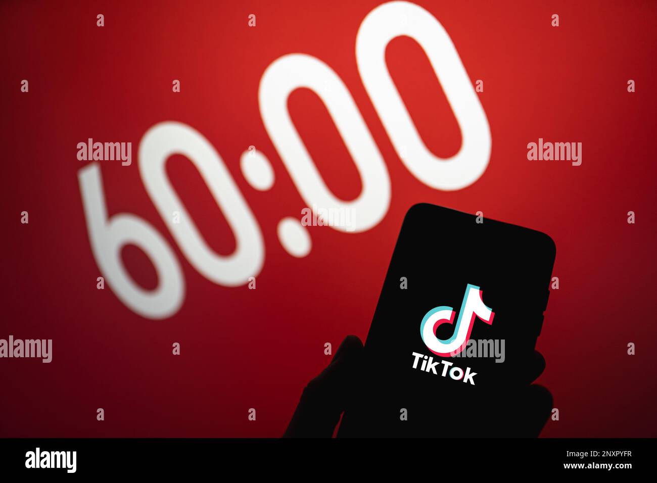 TikTok legt eine Zeitbegrenzung von einer Stunde für Benutzer unter 18 Jahren fest. TIK Tok App Logo auf dem Telefon neben 60 Minuten Text auf dem Hintergrund. Swansea, Großbritannien - 1. März 2023. Stockfoto