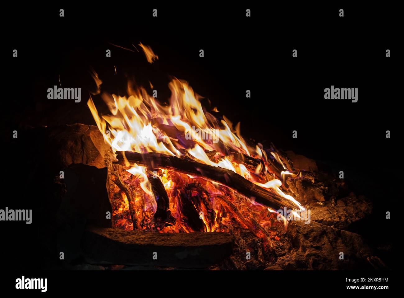Lagerfeuer bei Nacht mit dunklem Hintergrund und heißem Kohlebett Stockfoto