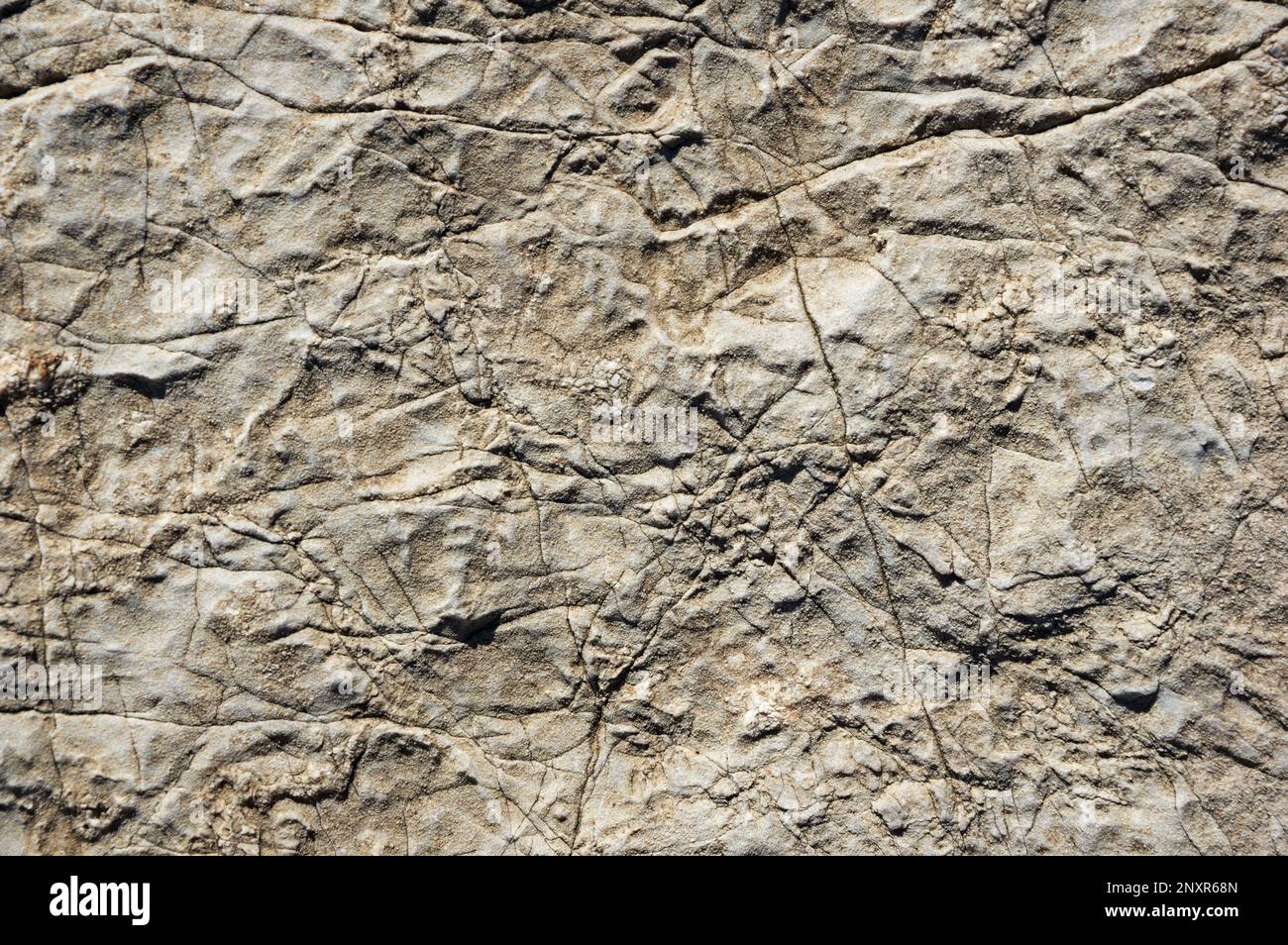 Risse und verwitterte graue Kalksteinhintergrundstruktur Stockfoto