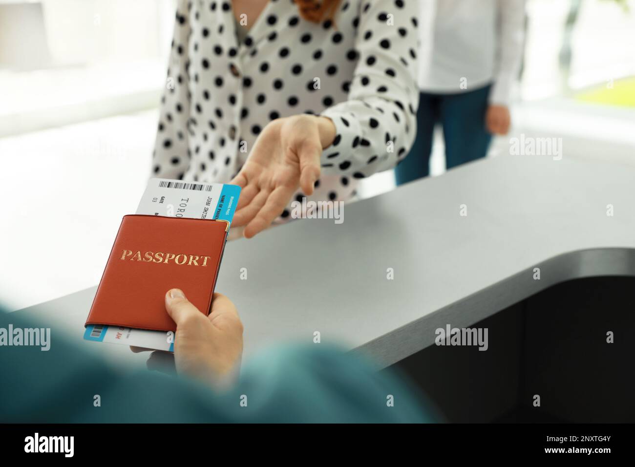 Ein Agent, der der Frau am Check-in-Schalter am Flughafen Pass und Ticket gibt Stockfoto