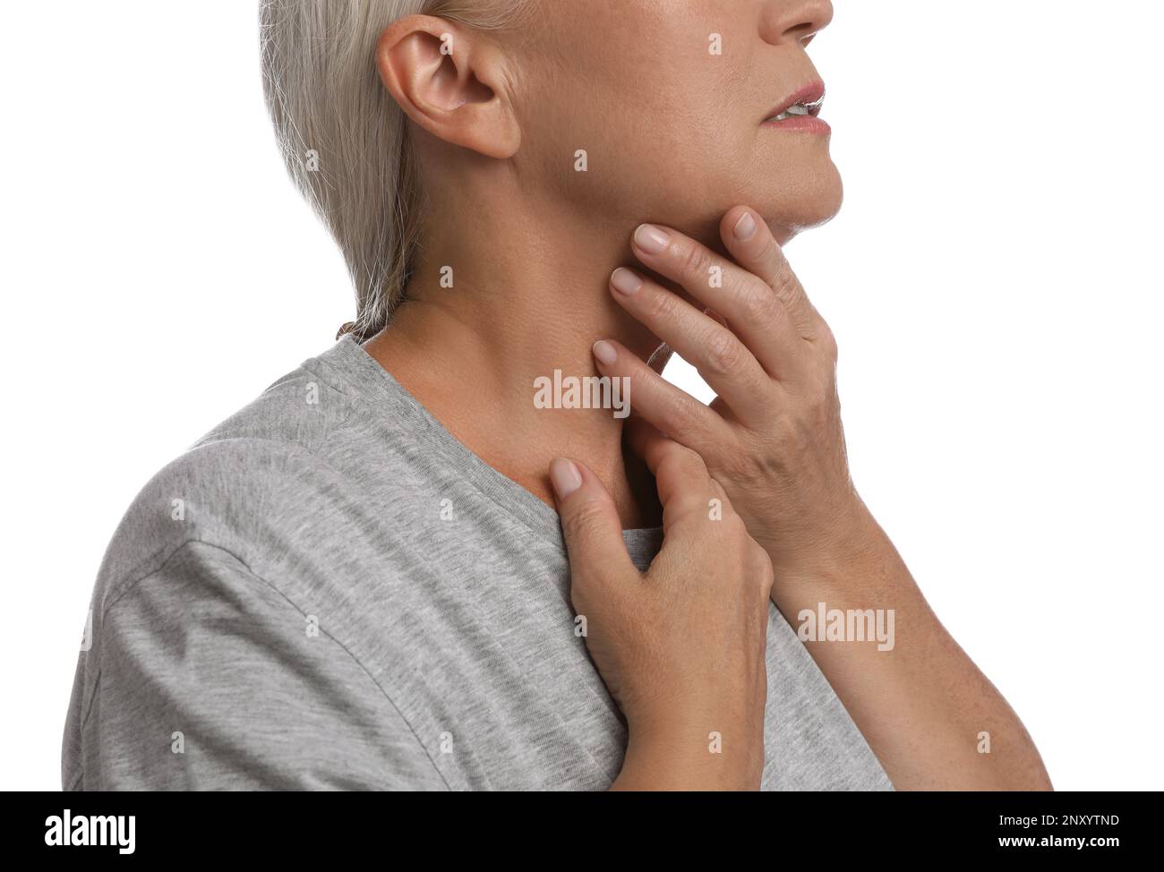 Reife Frau, die Schilddrüsen-Selbstuntersuchung auf weißem Hintergrund macht, Nahaufnahme Stockfoto