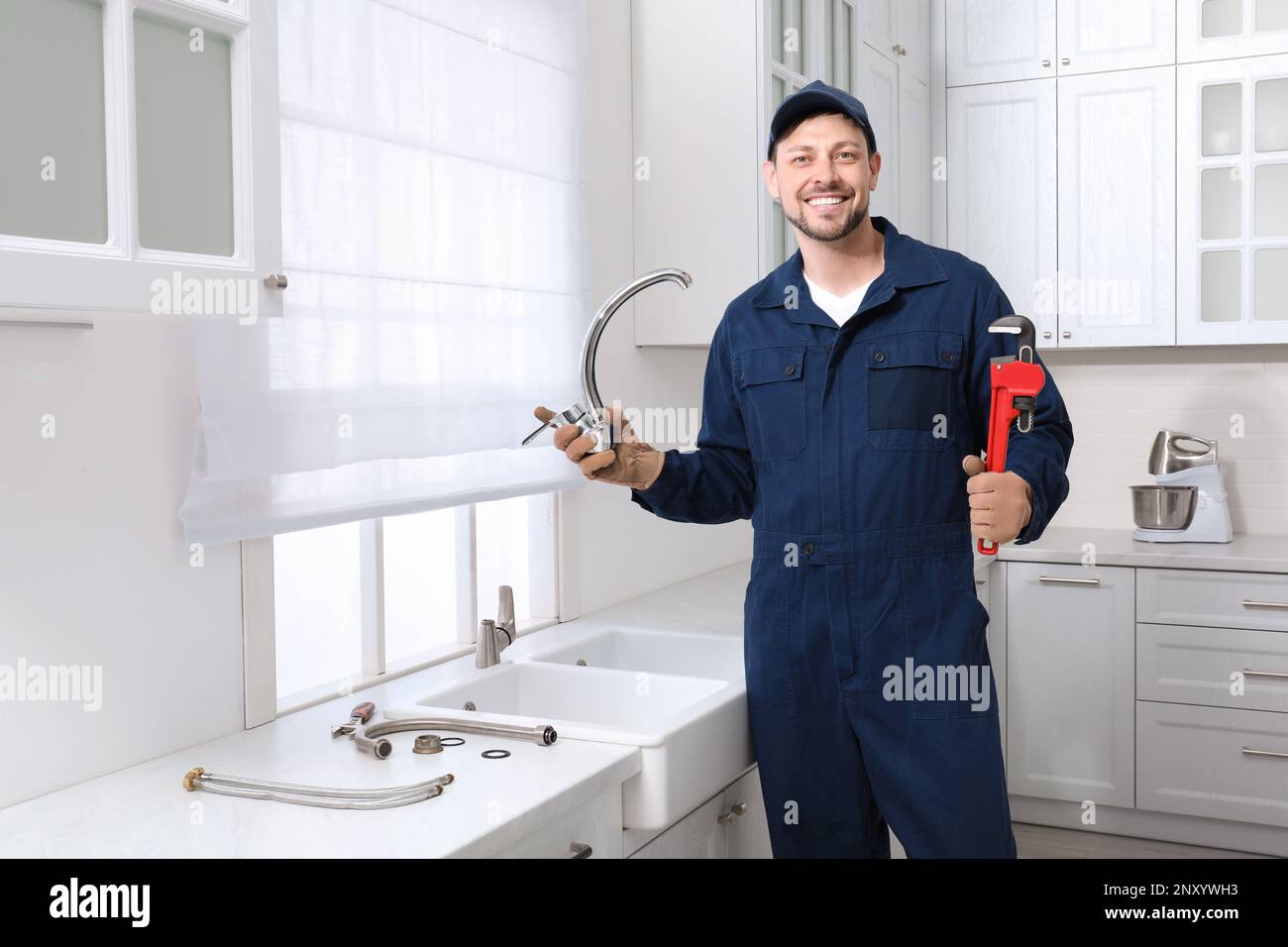 Professioneller Klempner mit Wasserhahn und Schraubenschlüssel in der Küche Stockfoto