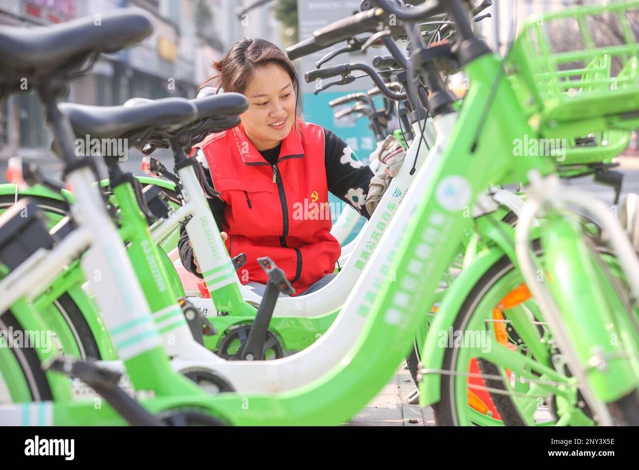 HUZHOU, CHINA - 2. MÄRZ 2023 - Ein Freiwilliger Reinigt öffentliche Fahrräder in der Wuyang Community in der Wuyang Street, Deqing County, Huzhou Stadt, Ostchina Zhe Stockfoto
