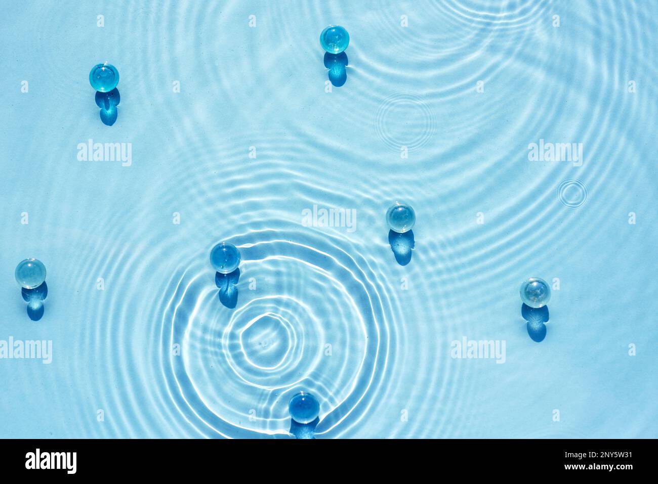 Wasserblauer Hintergrund mit Wellen- und Kreisstruktur und transparentem Granulat Stockfoto