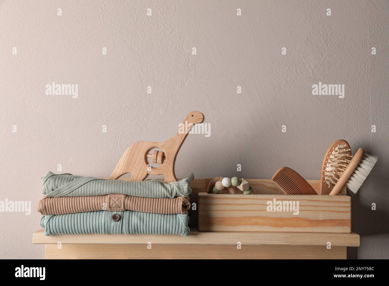 Babykleidung, Spielzeug und Accessoires auf einem Holzständer Stockfoto