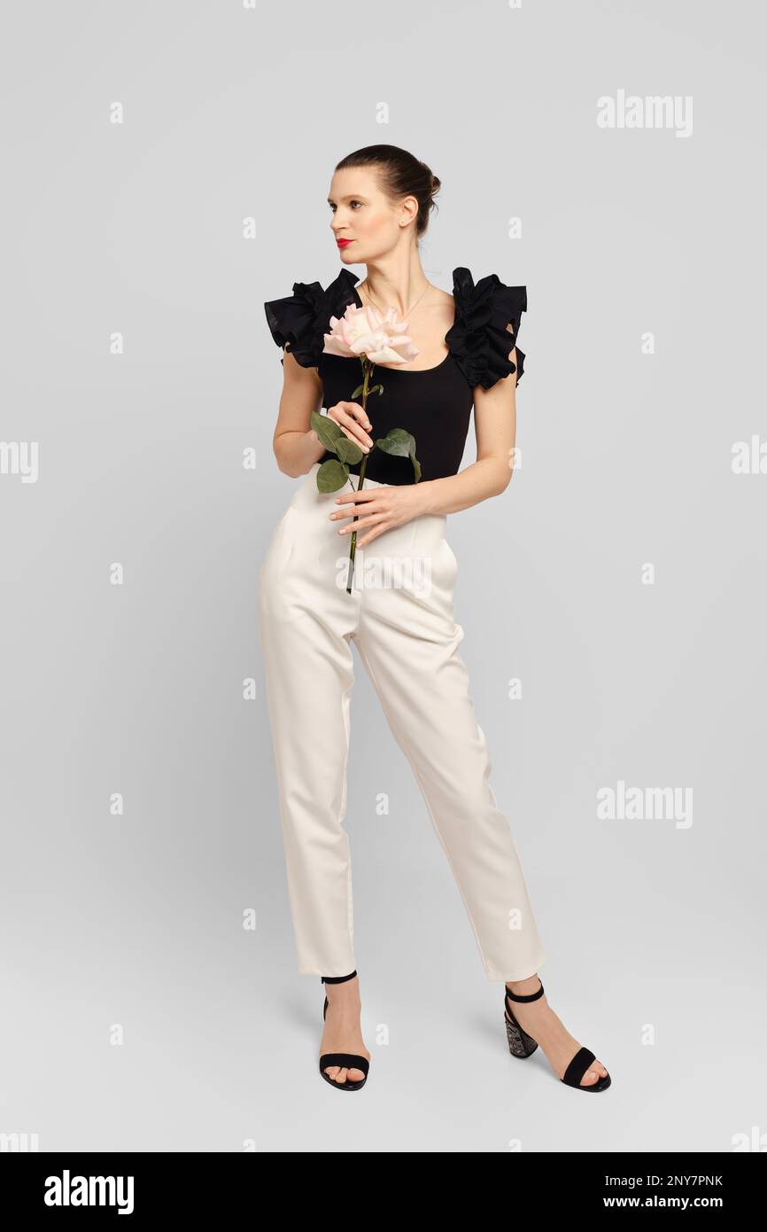 Stilvolle Erwachsene Frau, die in einem weißen Studio posiert, mit Blumen in den Händen Stockfoto
