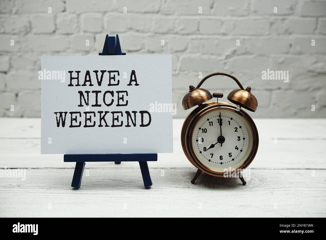 Genießen Sie ein schönes Wochenende mit Text und Wecker auf weißen Backsteinwänden und Holzhintergrund Stockfoto