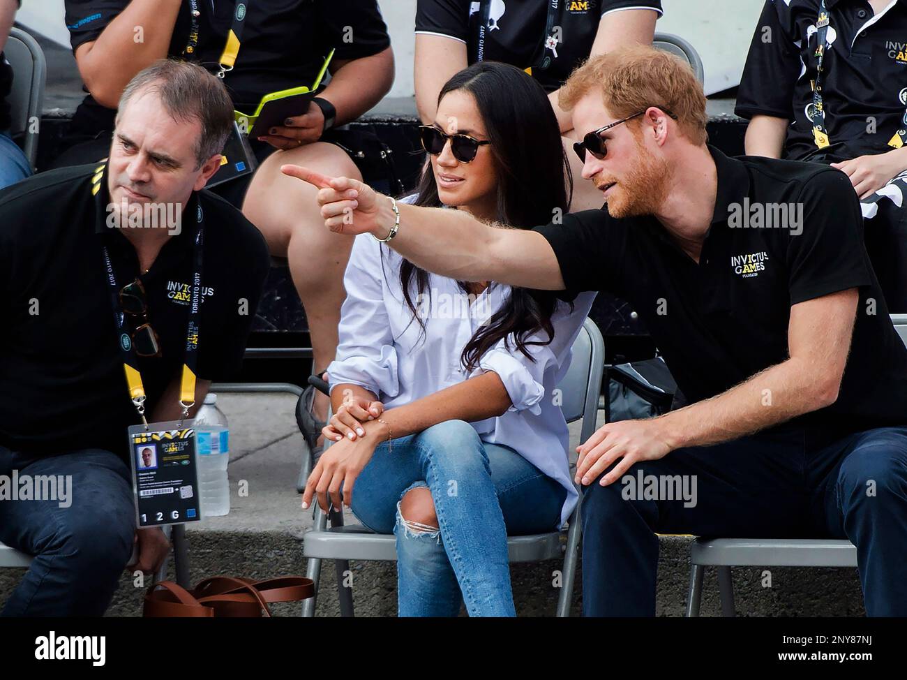 Prince Harry, right and his girlfriend Meghan Markle, center, watch the wheelchair tennis competition at the Invictus Games in Toronto on Monday, Sept. 25, 2017. (Nathan Denette/The Canadian Press via AP) Stockfoto