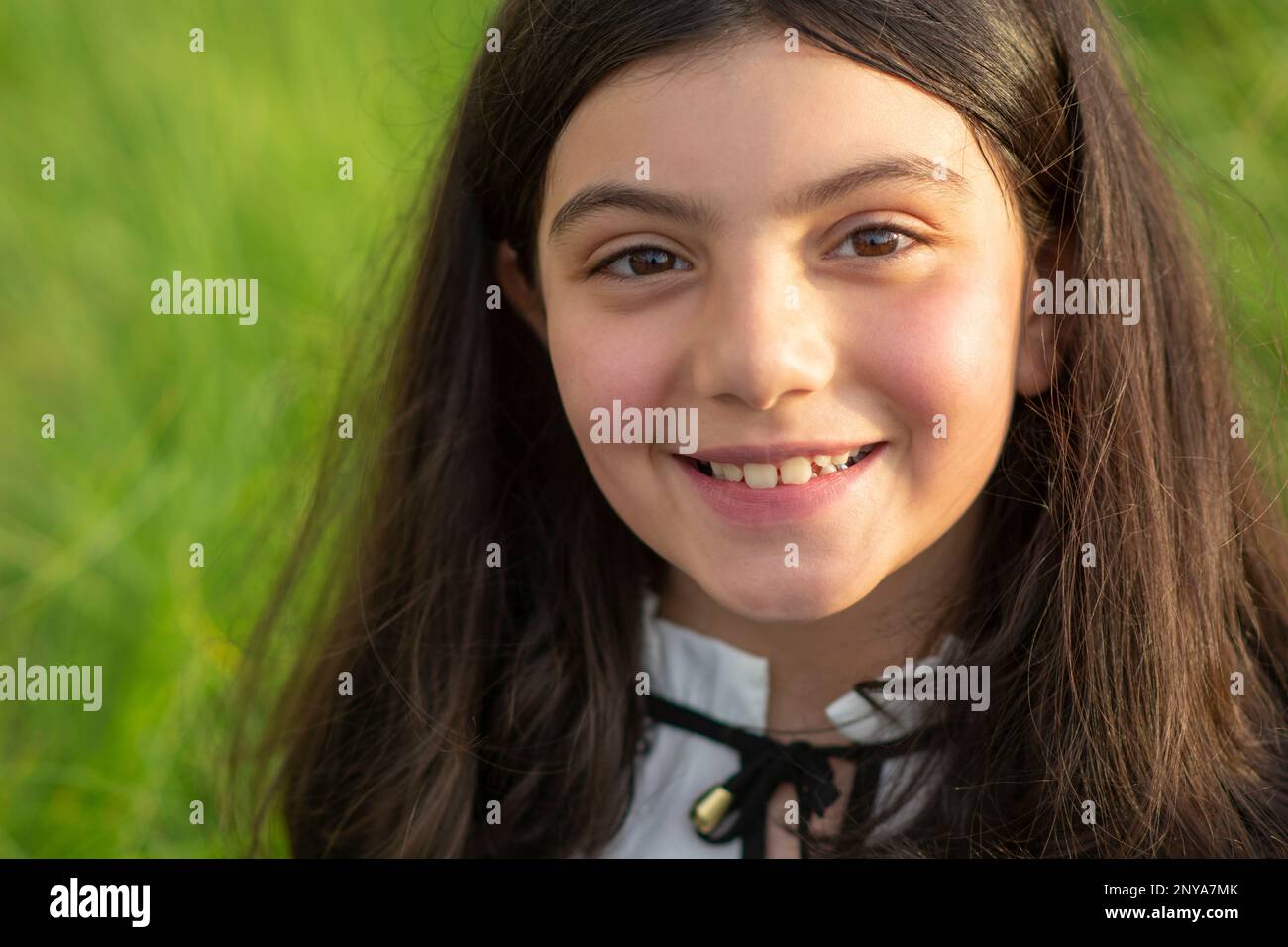 Glückliches kleines Mädchen, das draußen lächelt und in die Kamera schaut Stockfoto