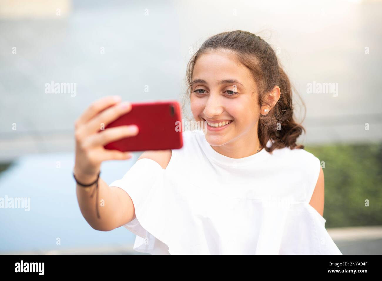 Glückliches Teenager-Mädchen, das draußen ein Selfie mit dem Smartphone macht Stockfoto