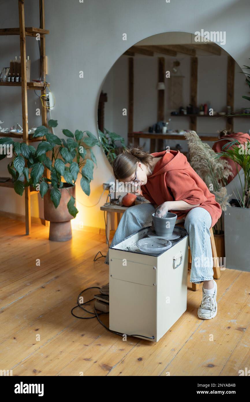 Handwerkerin genießt meditativen Prozess der Keramikherstellung, Formen von Lehm auf Töpferrad Stockfoto