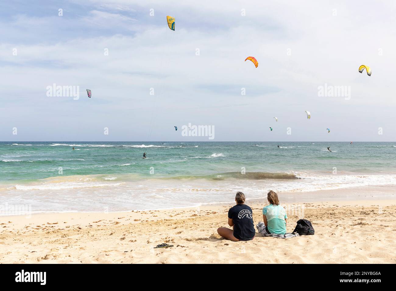 Zwei Touristen schauen auf die Kitesurfer an einem beliebten Kitesurfstrand in der Nähe der Stadt Santa Maria auf der Insel Sal, Cabo verde Archipel Stockfoto
