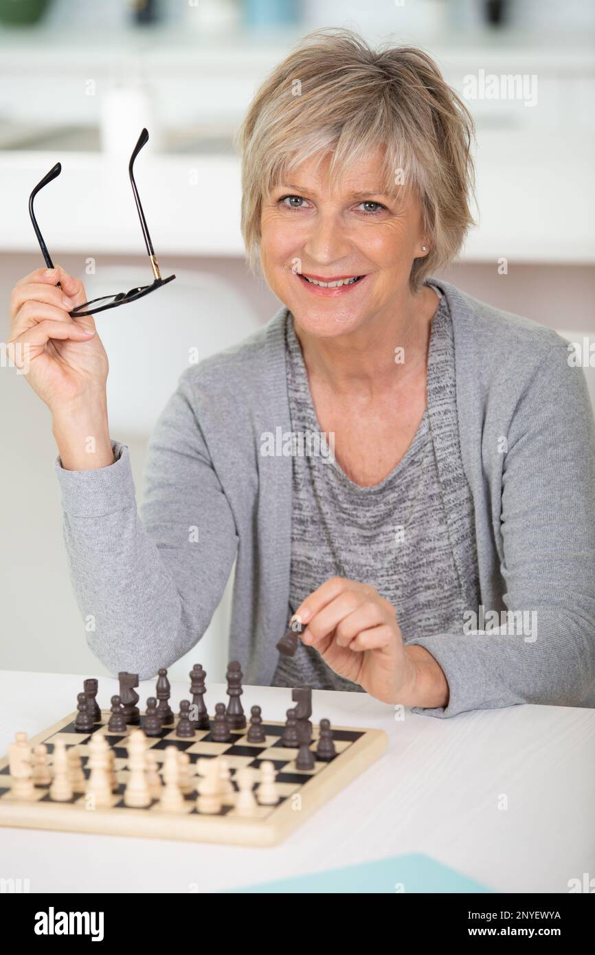 Glückliche Frau zu Hause, die allein Schach spielt Stockfoto