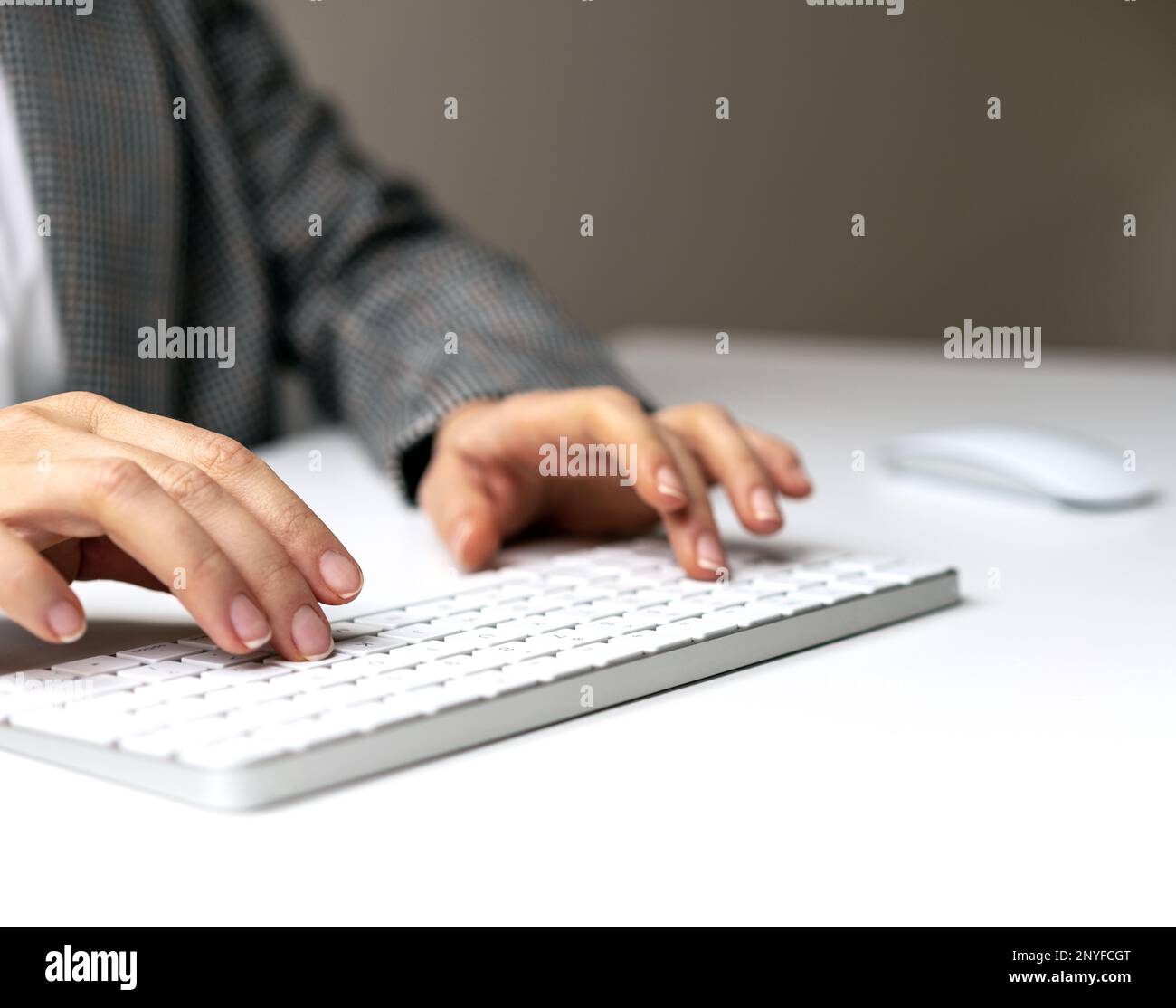 Weibliche Hände und drahtlose Computertastatur auf weißem Schreibtisch. Stockfoto