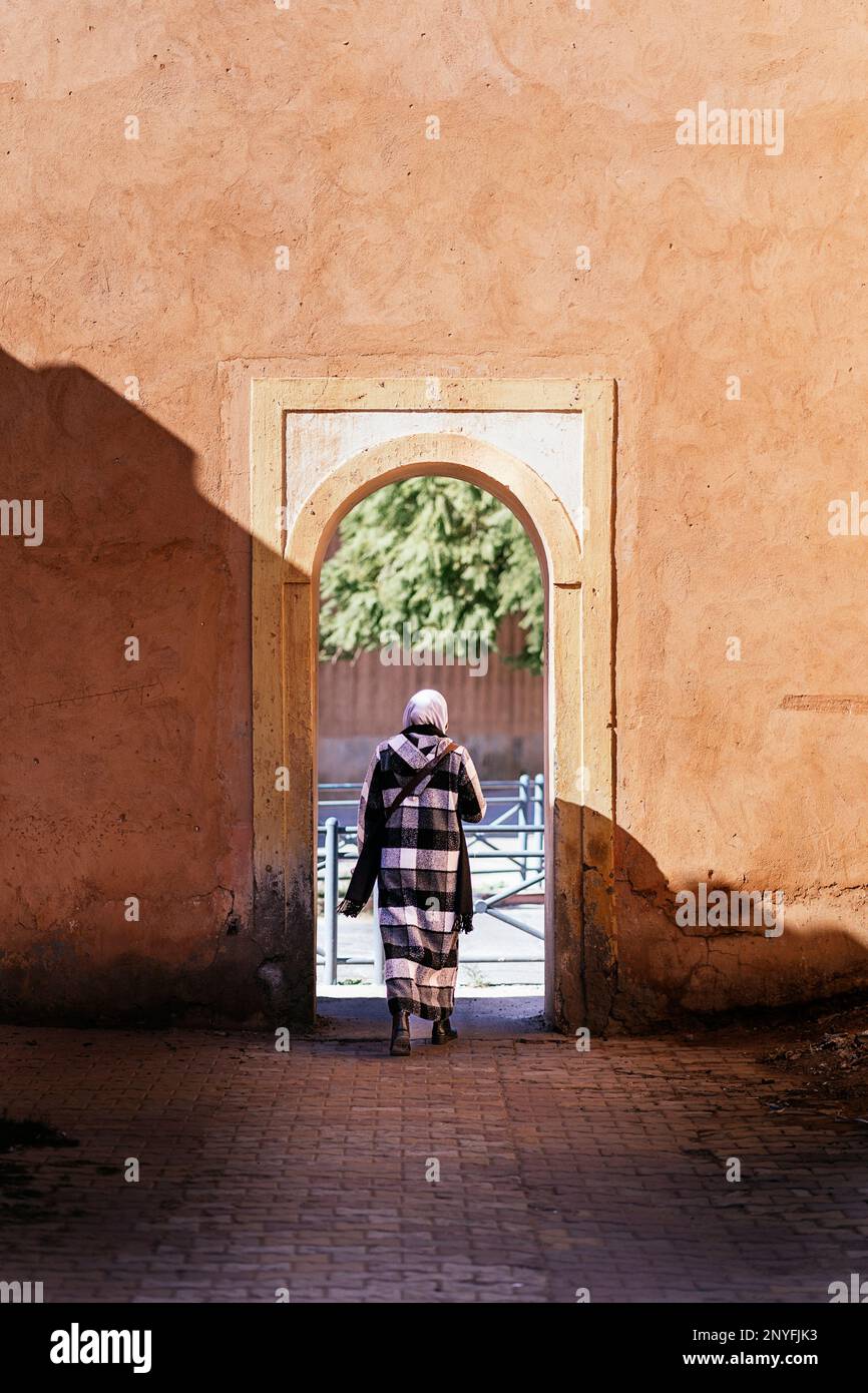 Rückblick auf anonyme weibliche Touristen, die durch eine gewölbte Passage des historischen Gebäudes in Mauretanien spazieren Stockfoto