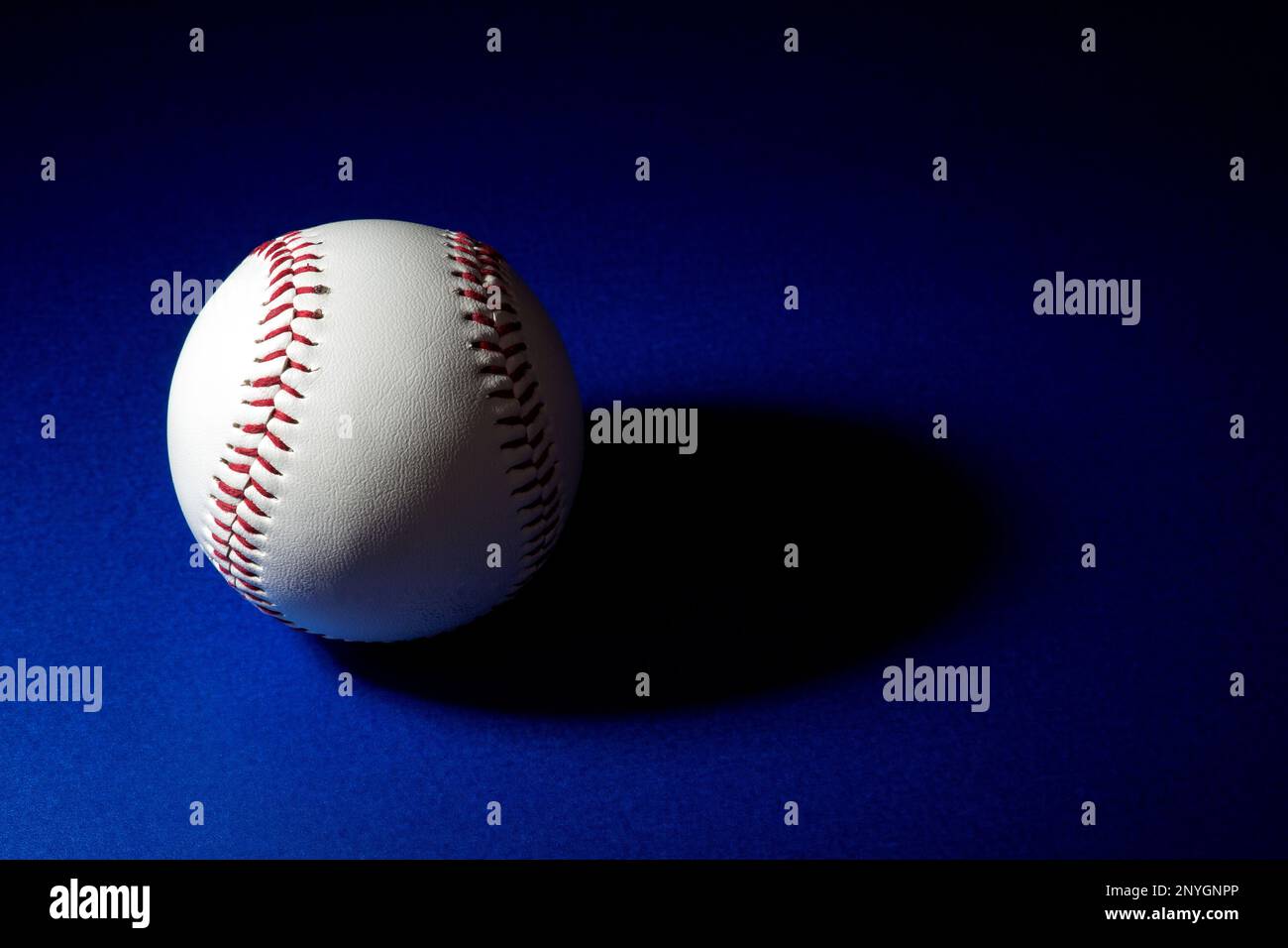 Softball teilweise beleuchtet mit Schatten auf blauem Hintergrund Stockfoto