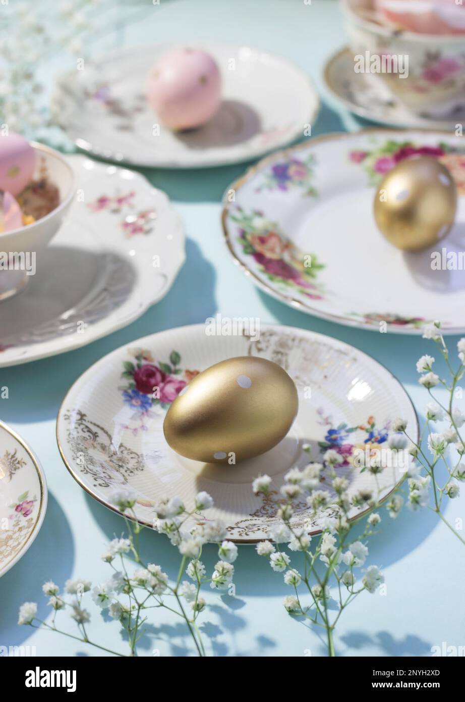 Ästhetische Osterzusammensetzung aus bunten Tellern und goldenen Eiern; Osterkonzept Stockfoto