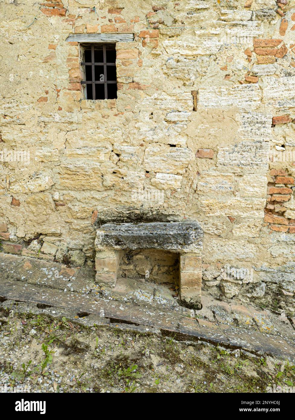 Steinbank an einem Hang unter einem versperrten Fenster in Lucignano d'Asso Stockfoto