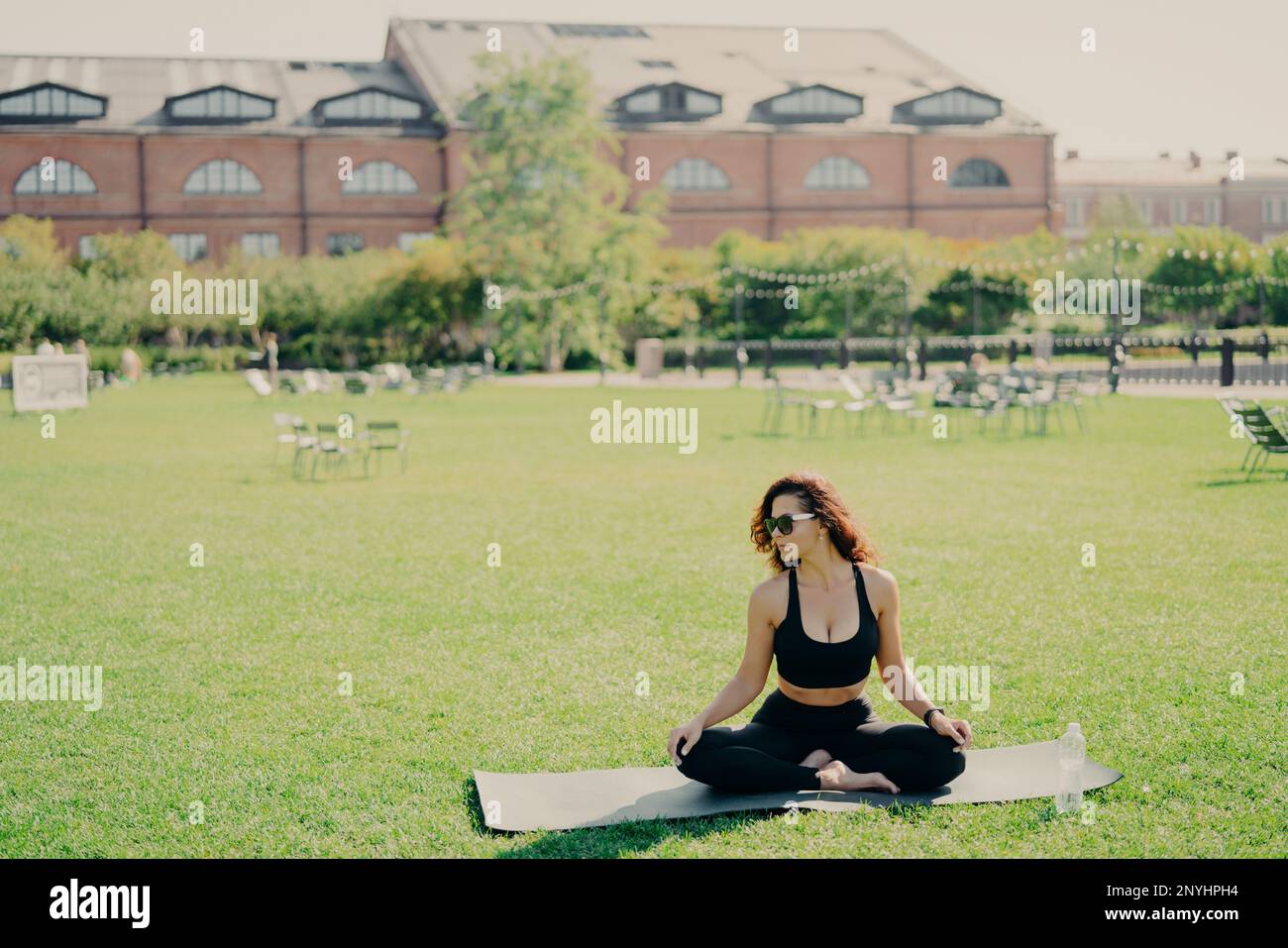 Entspannt schlank brünett Weiße Frau sitzt in Lotus Pose auf Fitnessmatte hat perfekte Körperform Yoga und Meditation trägt Sportkleidung Posen Stockfoto