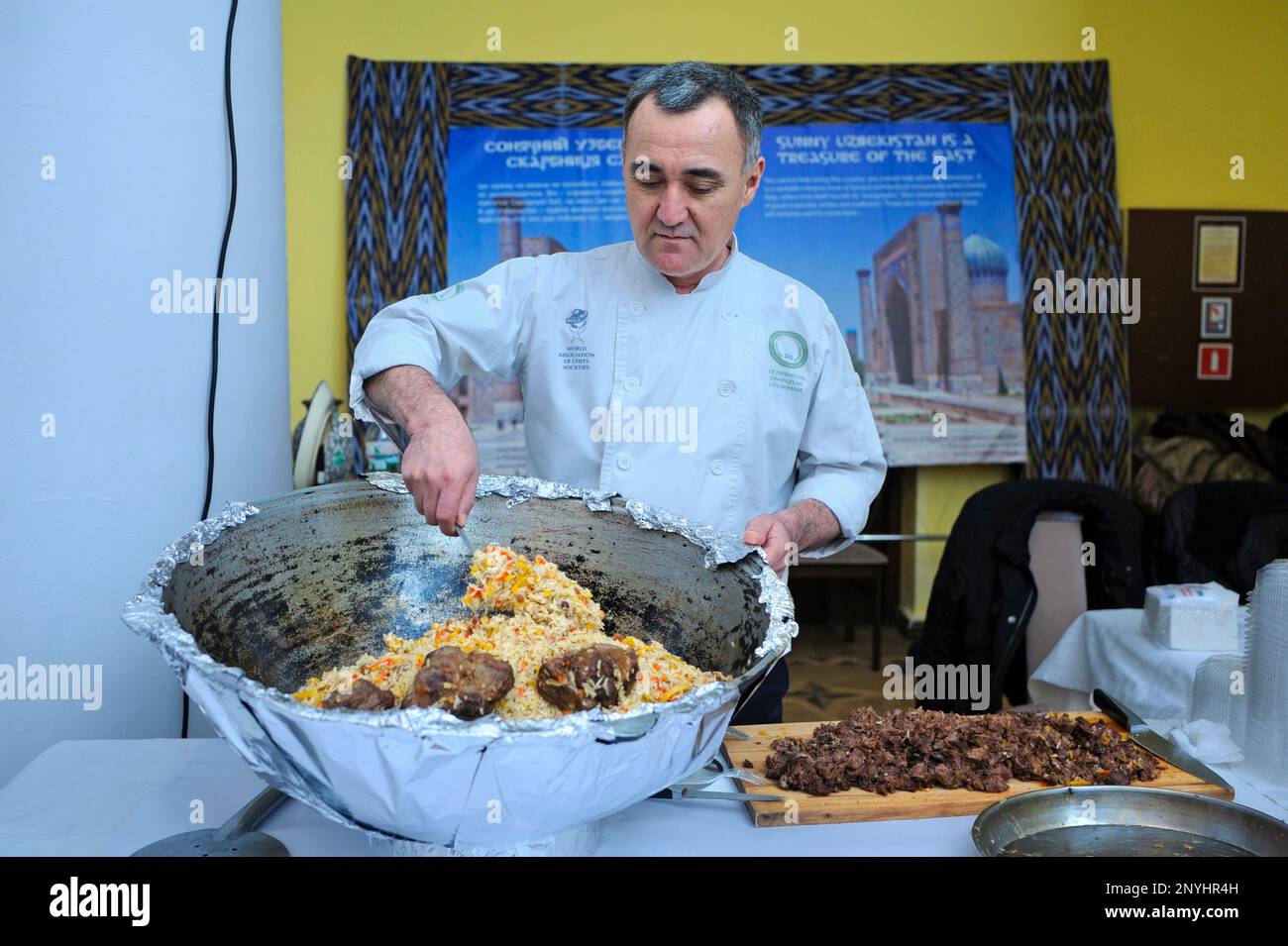 Ein asiatischer Koch kocht usbekischen Pilaf in einem großen Kessel. Festival der orientalischen Kultur. Kiew, Ukraine Stockfoto