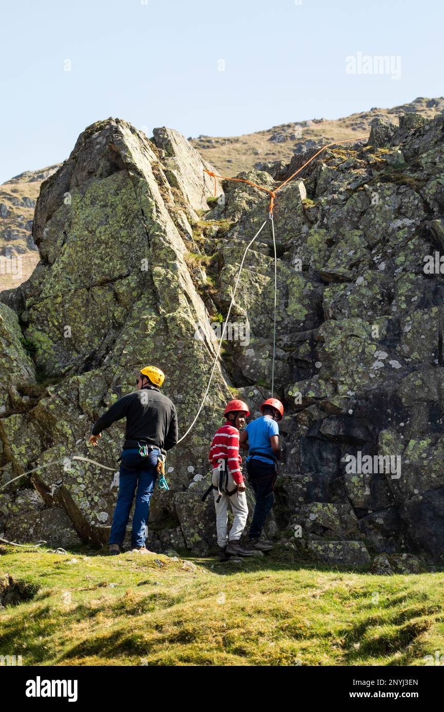 Schulkinder aus der Innenstadt, denen das Klettern in einem alten Steinbruch im Coombs Martindale Ullswater, dem Lake District, Cumbria, beigebracht wird Stockfoto