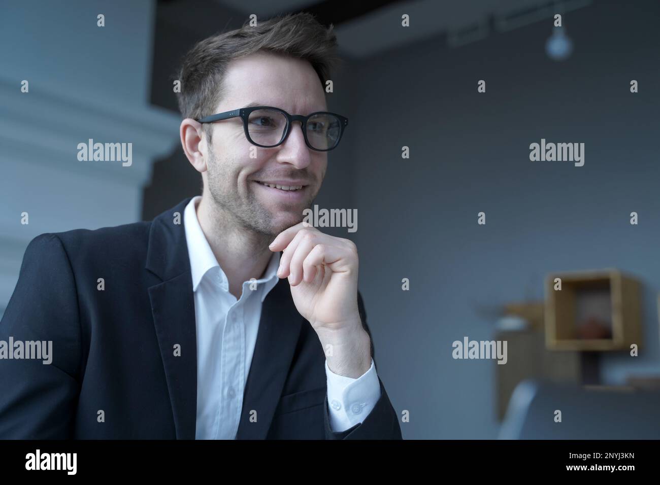 Gutaussehender positiver österreichischer Geschäftsmann trägt eine Brille, die von zu Hause aus arbeitet, freiberufliche Arbeit auf einem Laptop genießt, Publikationen liest oder Stockfoto
