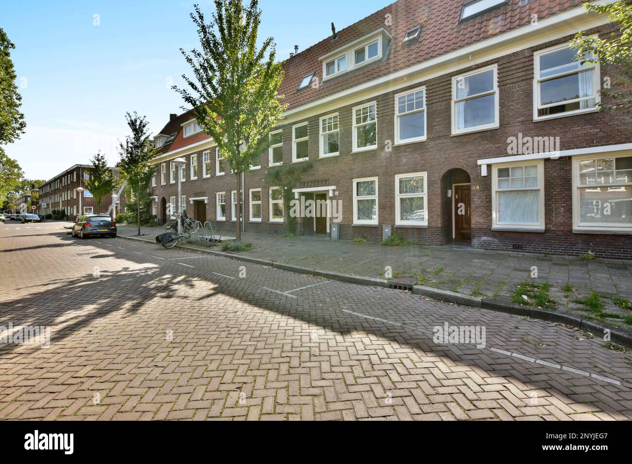 Amsterdam, Niederlande - 10. April 2021: Ein Backsteingebäude an der Seite einer Straße mit Autos, die vor dem Hotel geparkt sind und hinter denen Bäume den Bürgersteig säumen Stockfoto