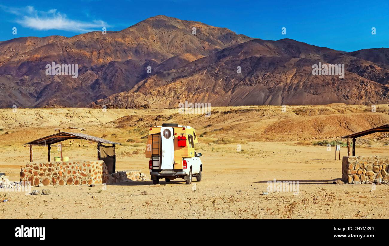 Einsamer, leerer, wilder Strand Campingplatz mit Steinkamin, trockenen Bergen, Wohnwagen - Chile, Atacama Region, Pan de Azucar Stockfoto