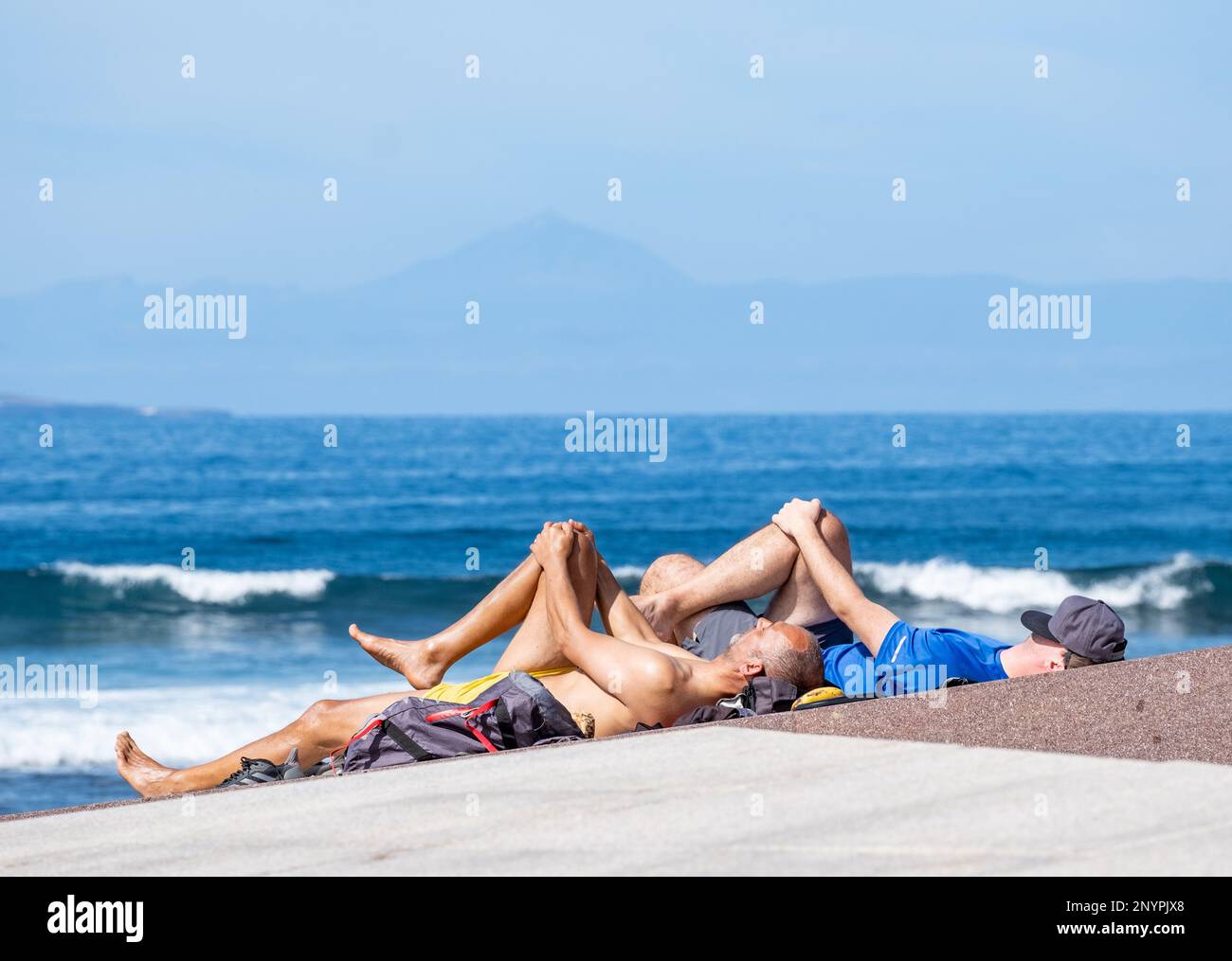 Gran Canaria, Kanarische Inseln, Spanien. 2. März 2023 28 Grad Celsius und perfekte Wellen für Surfer am weltberühmten Surfstrand El Confital auf Gran Canaria. IM BILD: Surfer, die sich ausdehnen, bevor es mit Spaniens höchstem Berg, El Teide, in der Ferne auf Teneriffa losgeht. Kredit: Alan Dawson/Alamy Live News Stockfoto