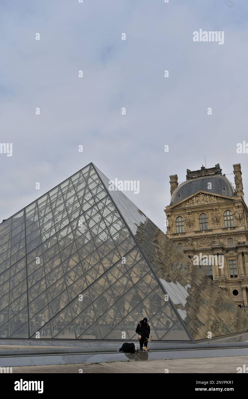 Unbekannte Straßenverkäufer von Reproduktionen des Eiffelturms selbst vor der Hauptpyramide des Louvre-Museums Stockfoto