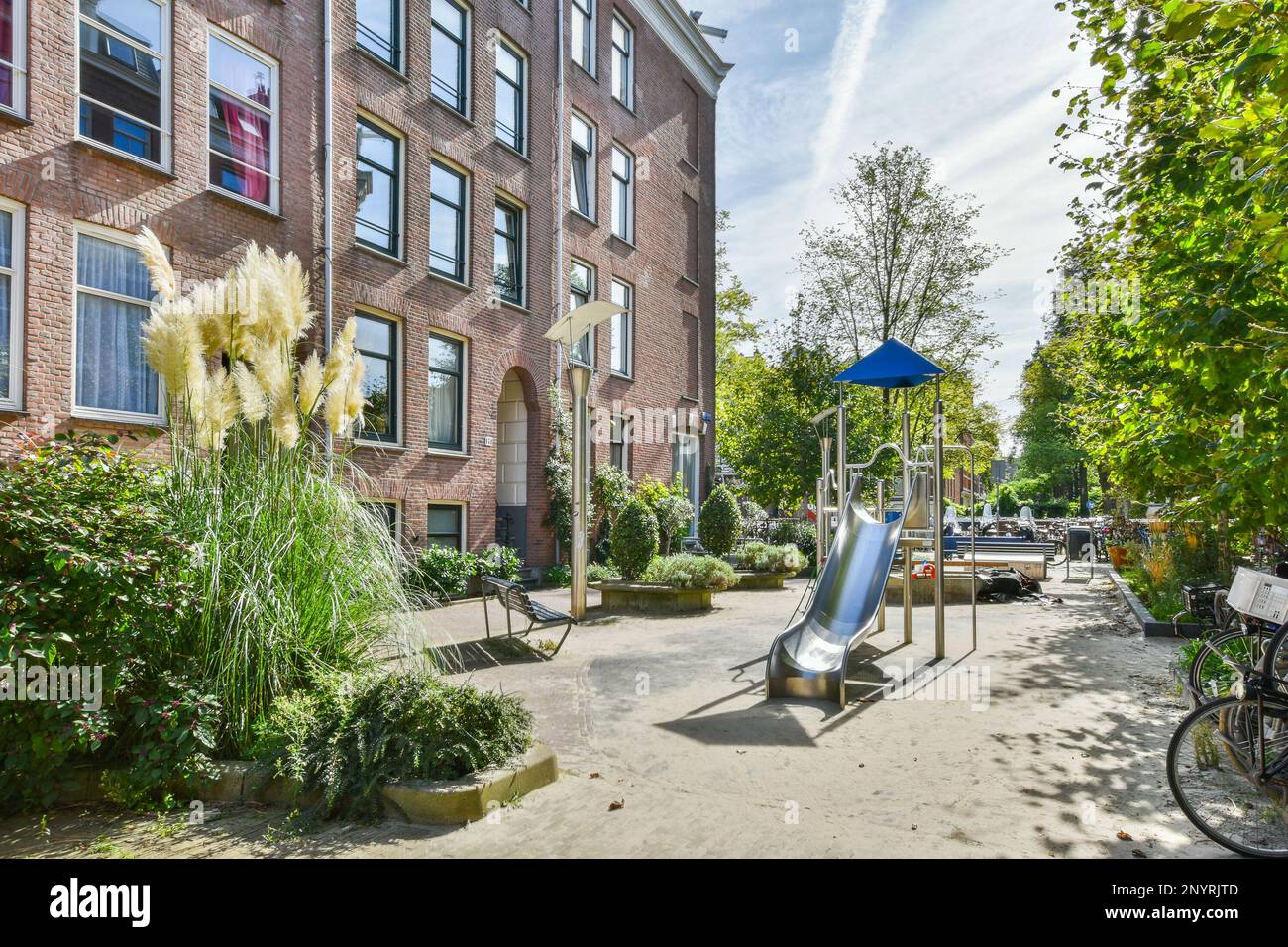 Amsterdam, Niederlande - 10. April 2021: Ein Spielplatz in der Mitte eines Apartmentkomplexes mit vielen Pflanzen und Bäumen auf beiden Seiten des Gebäudes Stockfoto