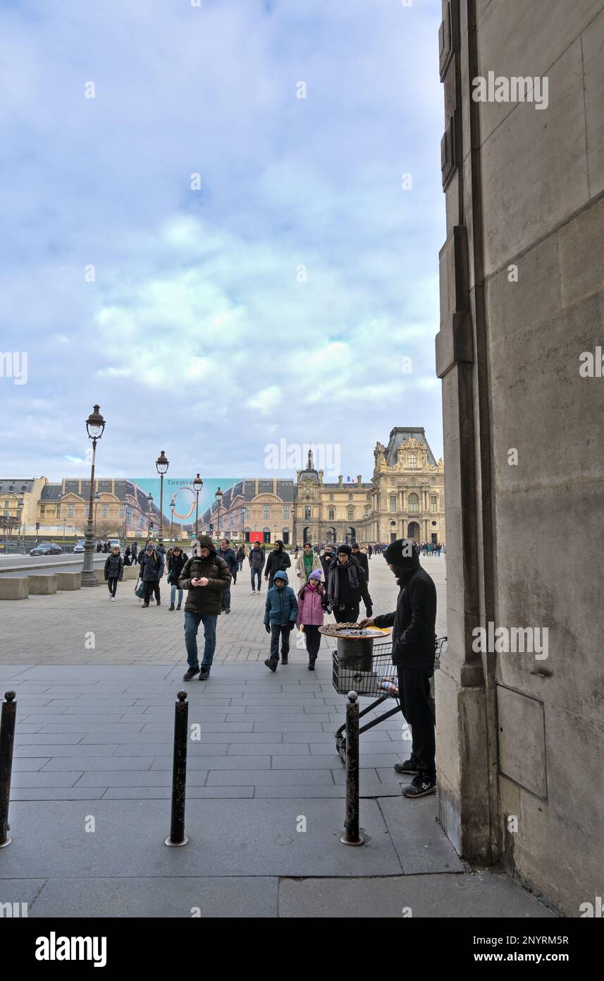 Straßenverkäufer, der Kastanien in einem Einkaufswagen für die Touristen in Paris röstet Stockfoto