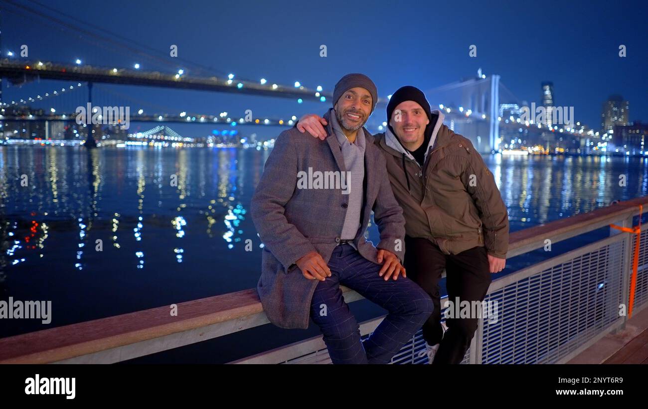 Freunde, die sich bei Nacht auf der Brooklyn Bridge entspannen - Straßenfotografie Stockfoto