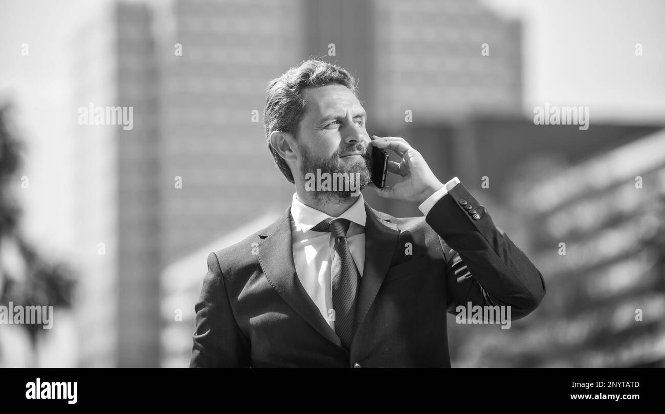 Erfolgreicher Geschäftsmann im Anzug, der telefoniert, draußen steht, Kommunikation. Stockfoto