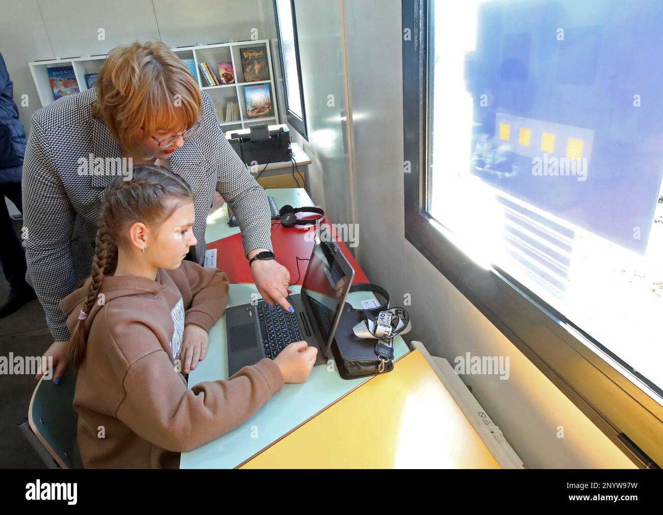 ZAHALTSI, UKRAINE - 2. MÄRZ 2023 - die stellvertretende Schulleiterin Olena Lavruk zeigt auf den Bildschirm eines Laptops, während sie einem Schüler in der ersten modularen Ausbildung hilft Stockfoto