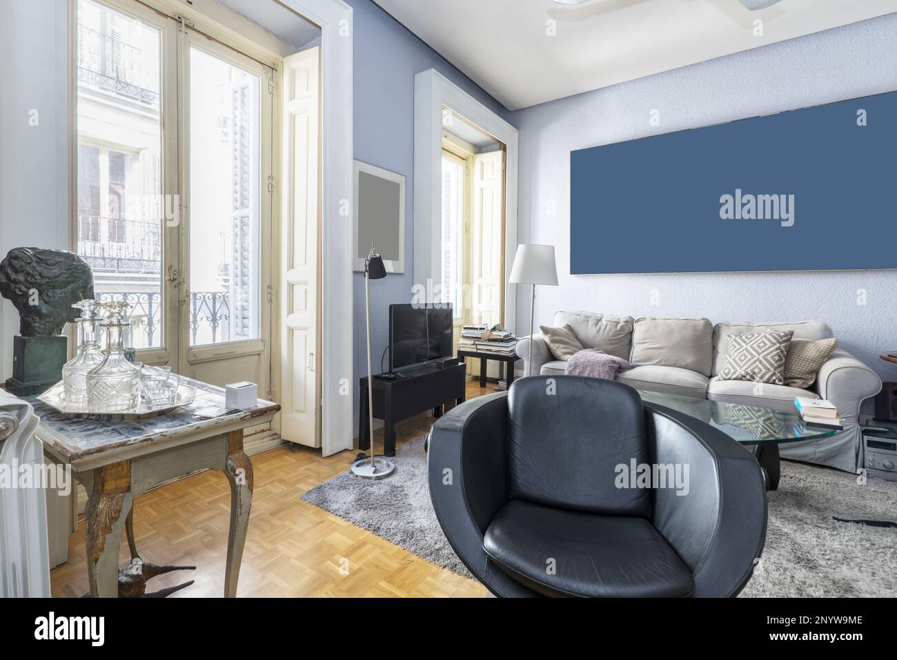 Wohnzimmer mit eklektischen Möbeln, sanften Farben und Balkon mit weißen Holzläden Stockfoto
