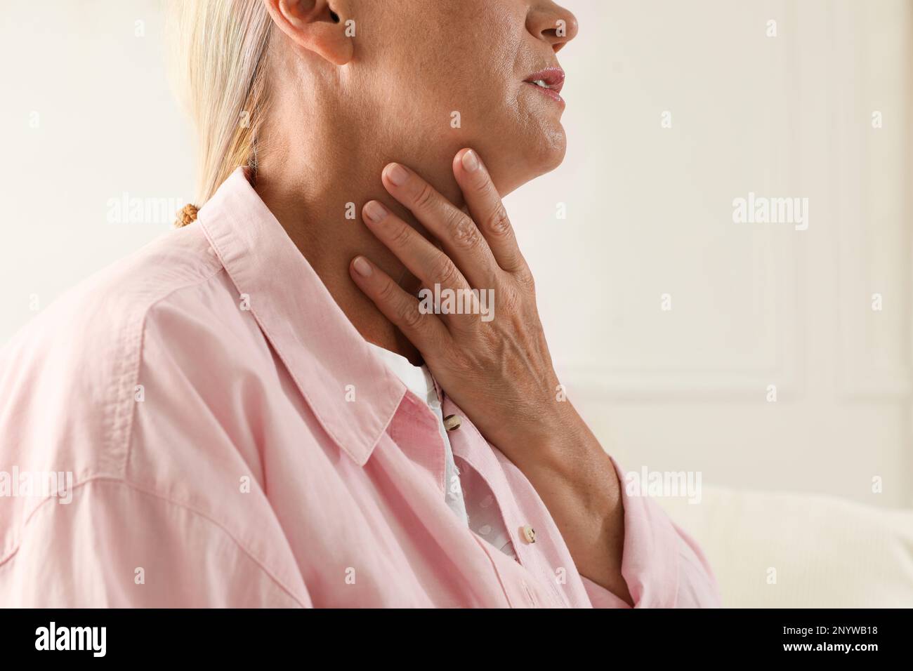 Reife Frau, die Schilddrüsen-Selbstuntersuchung vor hellem Hintergrund macht, Nahaufnahme Stockfoto