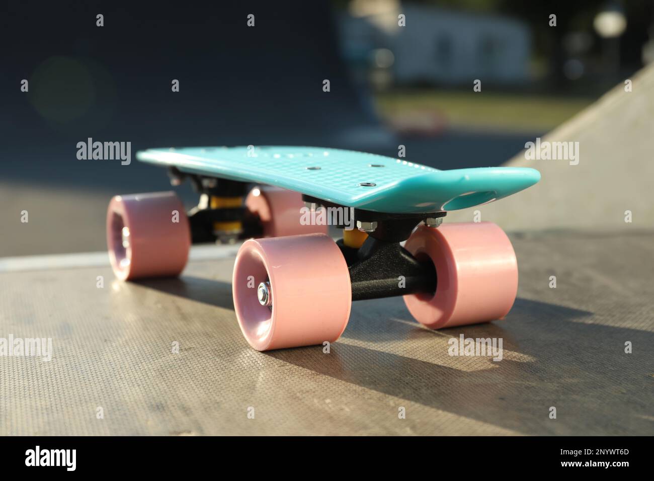 Modernes hellblaues Skateboard mit pinkfarbenen Rädern oben auf der Rampe im Freien, Nahaufnahme Stockfoto