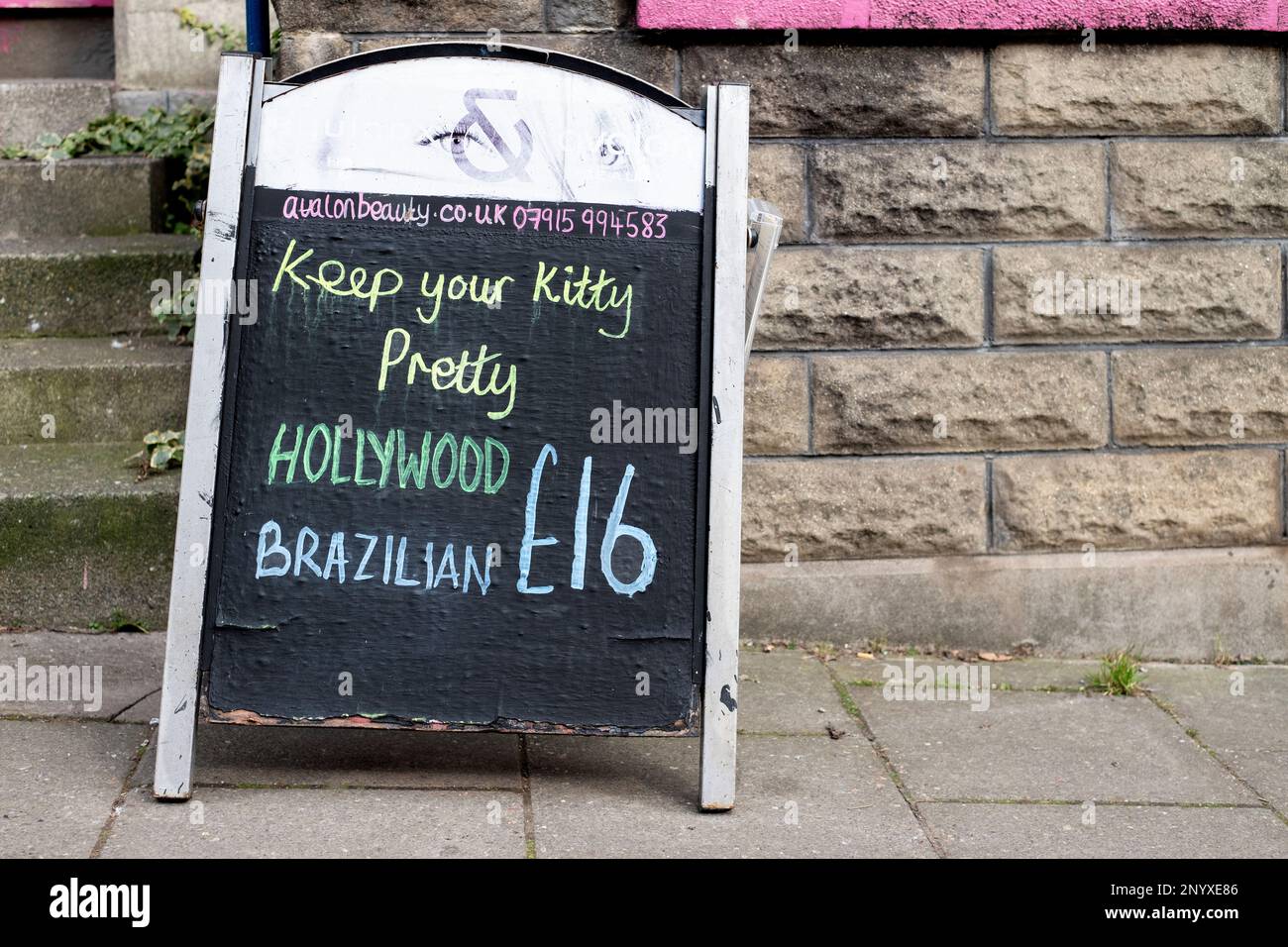 Eine humorvolle Kreide Ein Brett, das auf einer Straße der Stadt platziert wird, um intime wachsartige Haarentfernungsbehandlungen mit einem Hollywood oder Brasilianer zu einem ermäßigten Preis zu bewerben Stockfoto