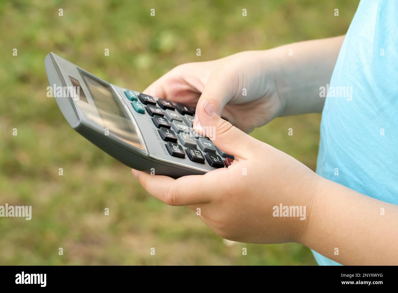 Anonymes Mädchen im Grundschulalter, Kind mit Taschenrechner, das es in den Händen hält, Objekt-Nahaufnahme, eine Person. STAMM, Mathematik, Mathematikunterricht Stockfoto