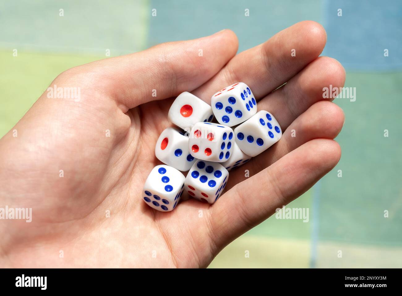 Ein Mann, der ein paar kleine Spielwürfel hält und verschiedene Zahlen in der Hand zeigt, eine Gruppe von Objekten aufnimmt. Mathematische Zufälligkeit, Entropie, Wahrscheinlichkeit und Statistik, e Stockfoto