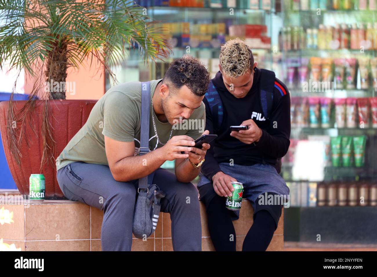 Zwei Typen sitzen mit Smartphones auf einer Straße. Online-Kommunikation im Freien Stockfoto